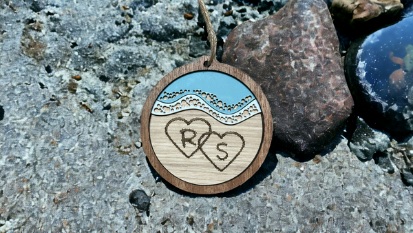 Beach Couple ornament, with initials drawn in the sand with waves ￼